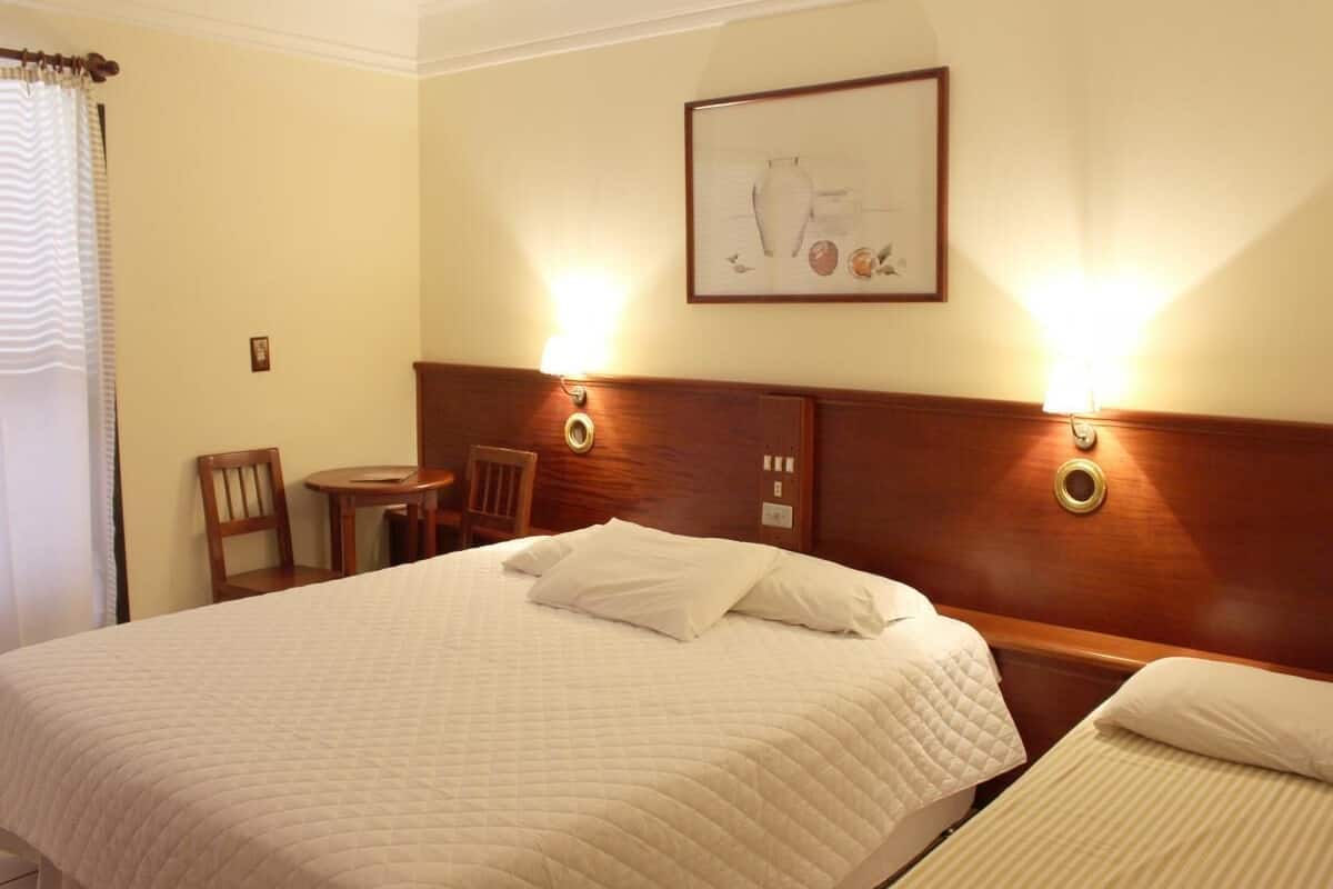Ett hotellrum med en stor säng, två sängbord, en stol och ett konstverk som hänger på väggen.