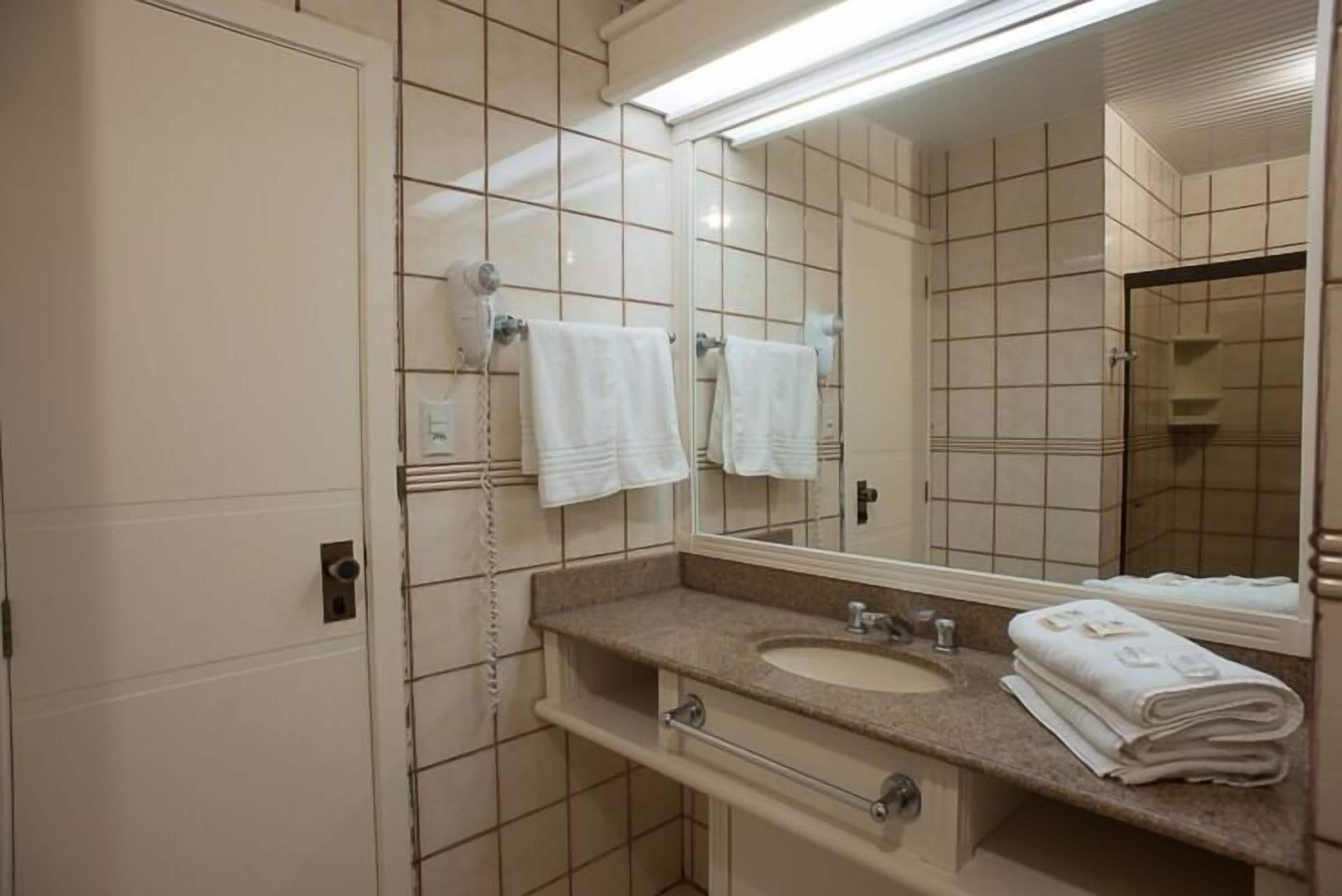 Un baño con lavamanos, espejo y perchero para toallas.