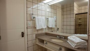 Un baño con lavamanos, espejo y perchero para toallas.