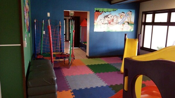 A playroom with colorful mats, a climbing net, and a mural on the wall. - Hotel Araçá (Capao da Canoa)