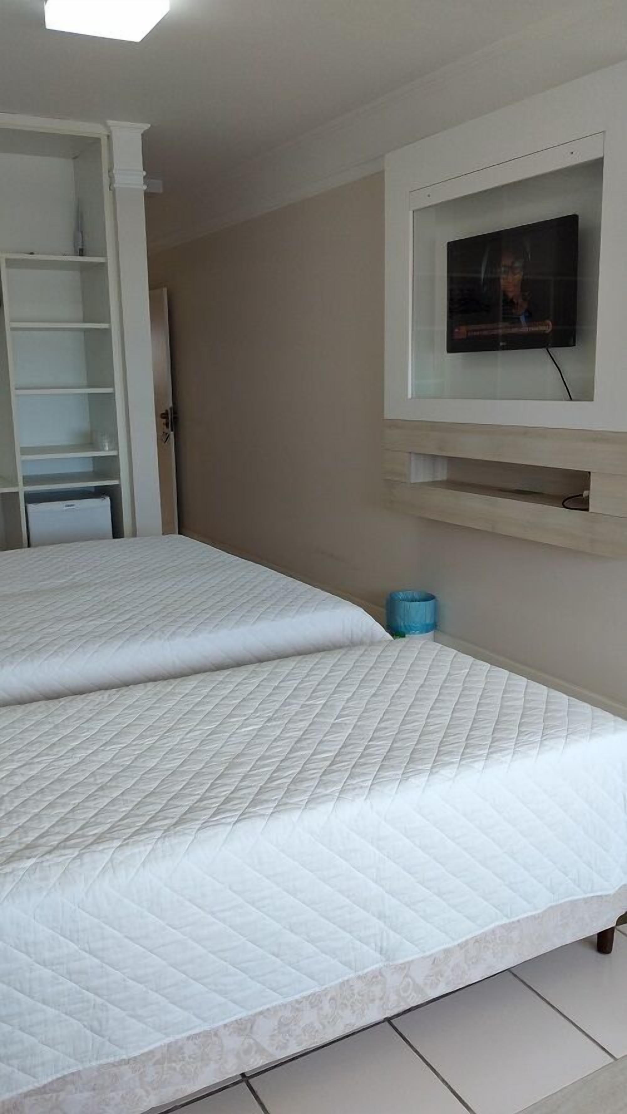 Quarto com uma cama grande, televisão na parede e guarda-roupa.