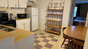 A compact kitchen with white cabinets, a microwave, a coffee maker, and a checkered floor.