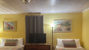 Una habitación con dos camas, un televisor, una lámpara y dos cuadros en las paredes.