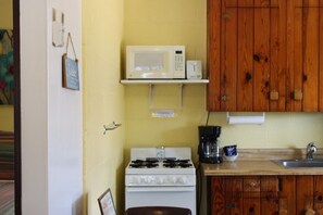 Une cuisine compacte équipée d’une cuisinière, d’un four à micro-ondes et d’une machine à café.