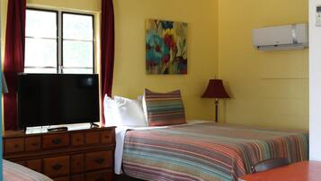 A room with a bed, a dresser, a television, and a painting on the wall.