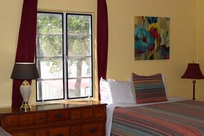 A bedroom with a bed, a dresser, a window with curtains, and a painting on the wall. - Sunfish Studio 8: Wi-Fi & Pool Access in Lake LBJ (Kingsland)