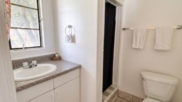 Et badeværelse med vask, toilet og et vindue.