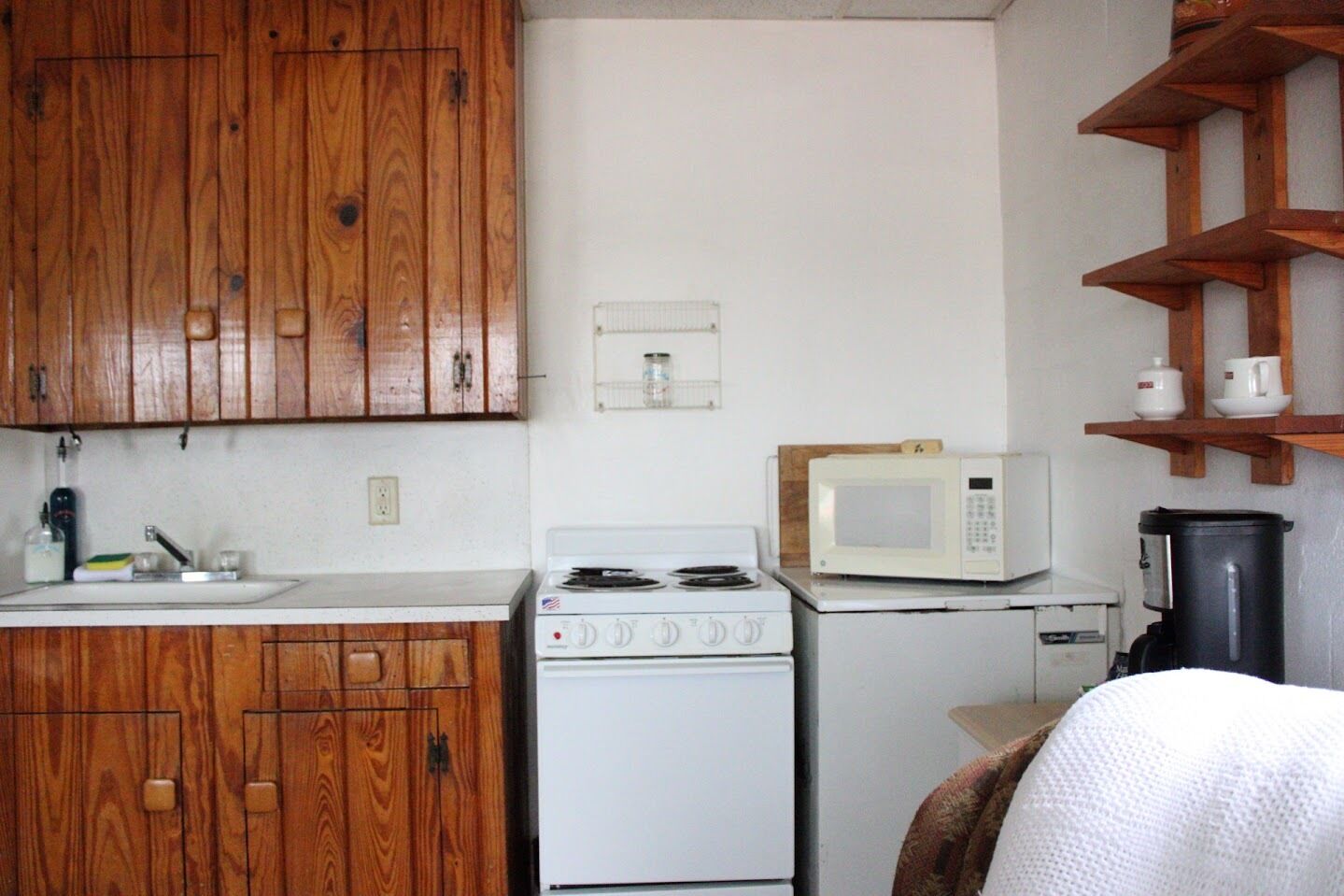 A kitchen with wooden cabinets, a white stove, a microwave, and a coffee maker.