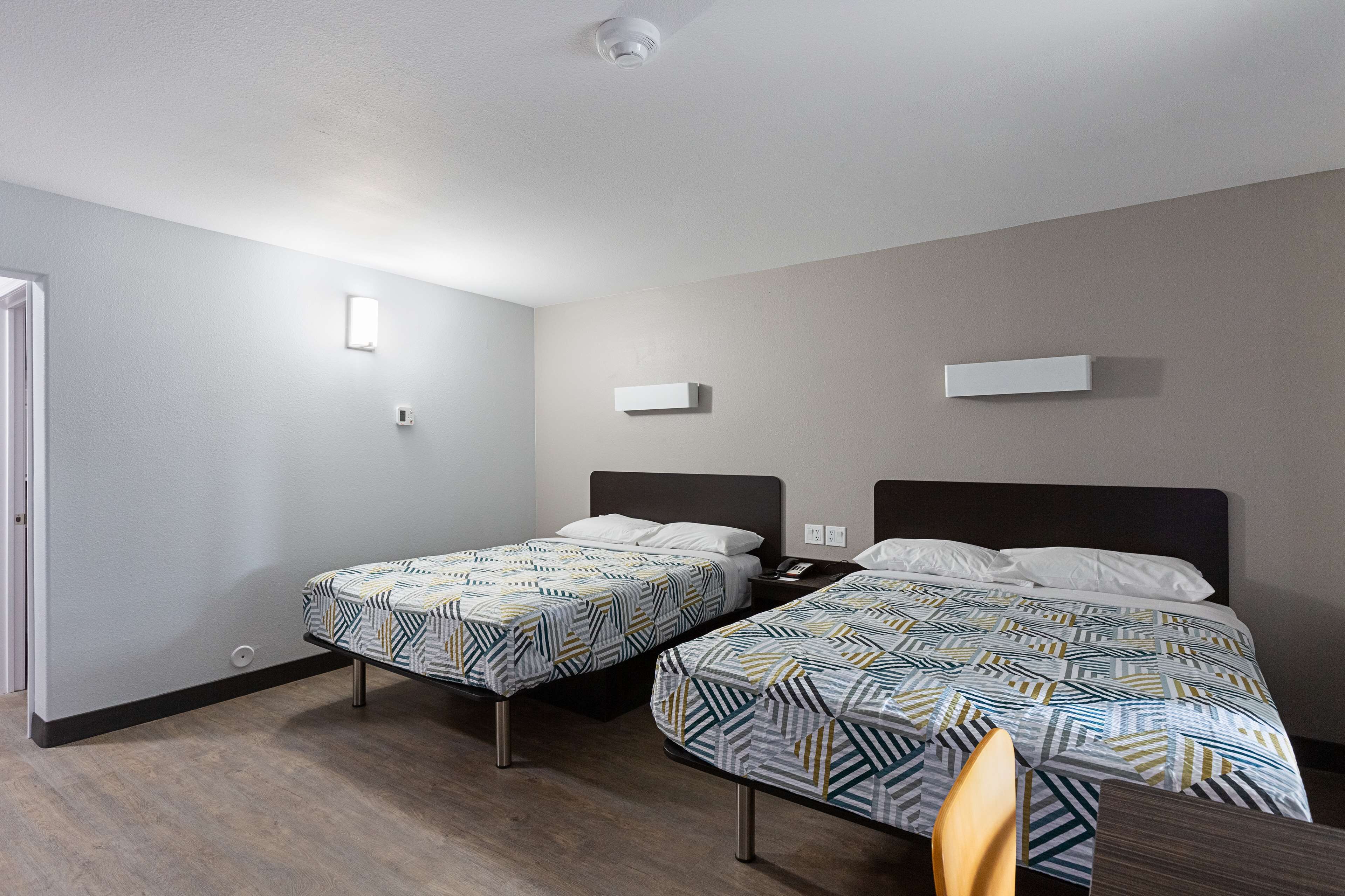 Habitación de hotel con dos camas individuales, un escritorio y una silla.