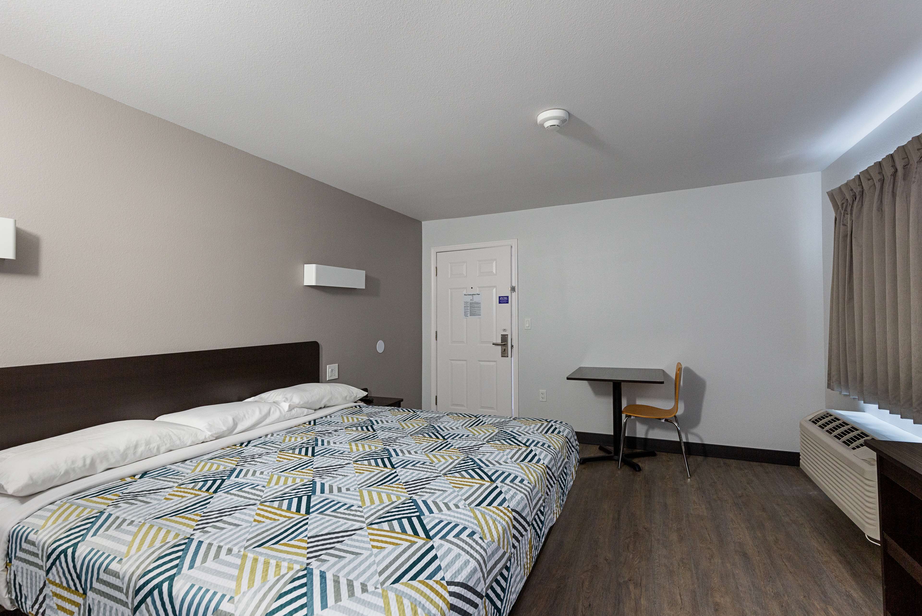 Ein Hotelzimmer mit Bett, Schreibtisch, Stuhl, Heizkörper und Tür.