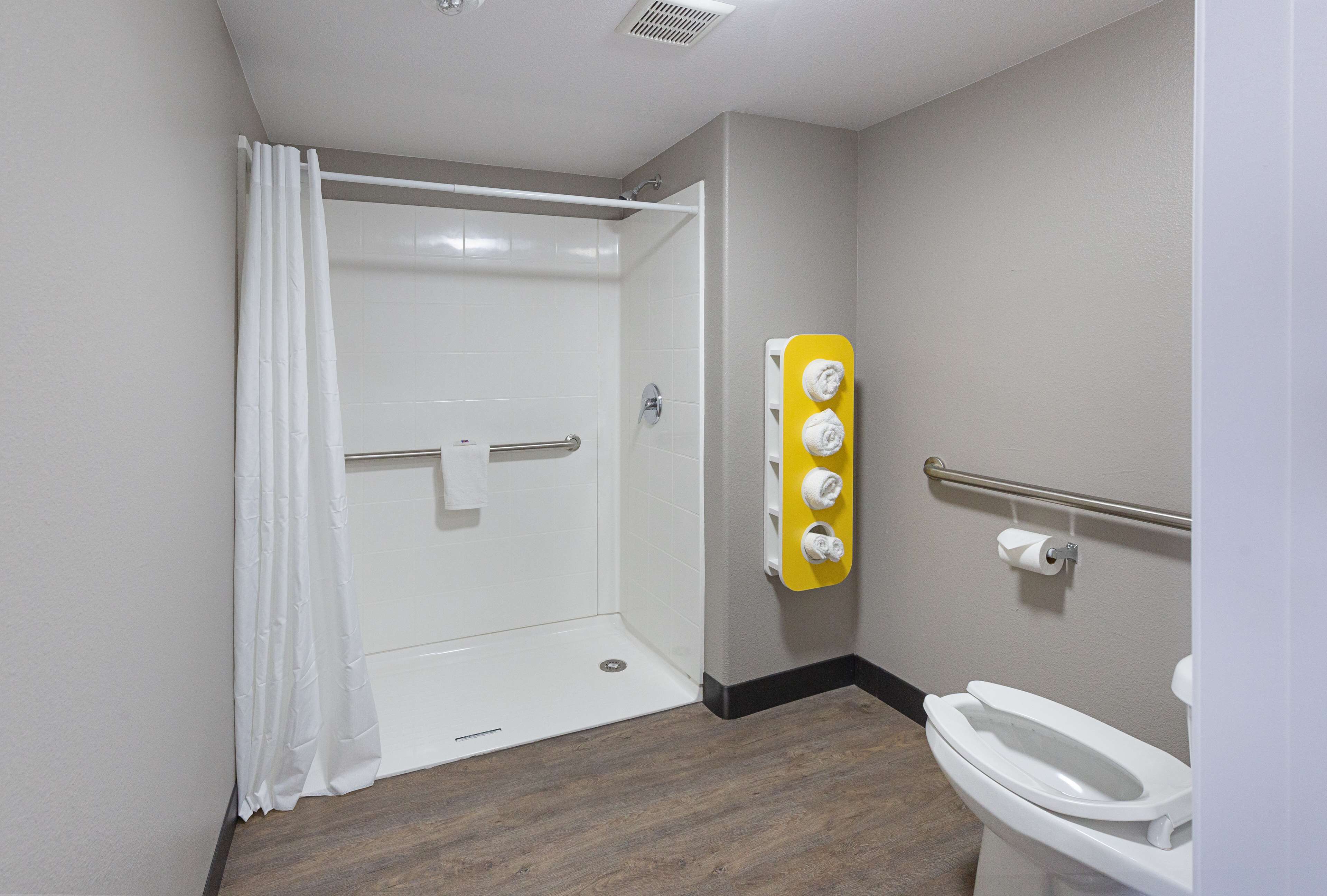 A bathroom with a shower, toilet, and a towel rack.