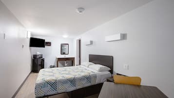 A hotel room with a bed, bedside table, and a desk.