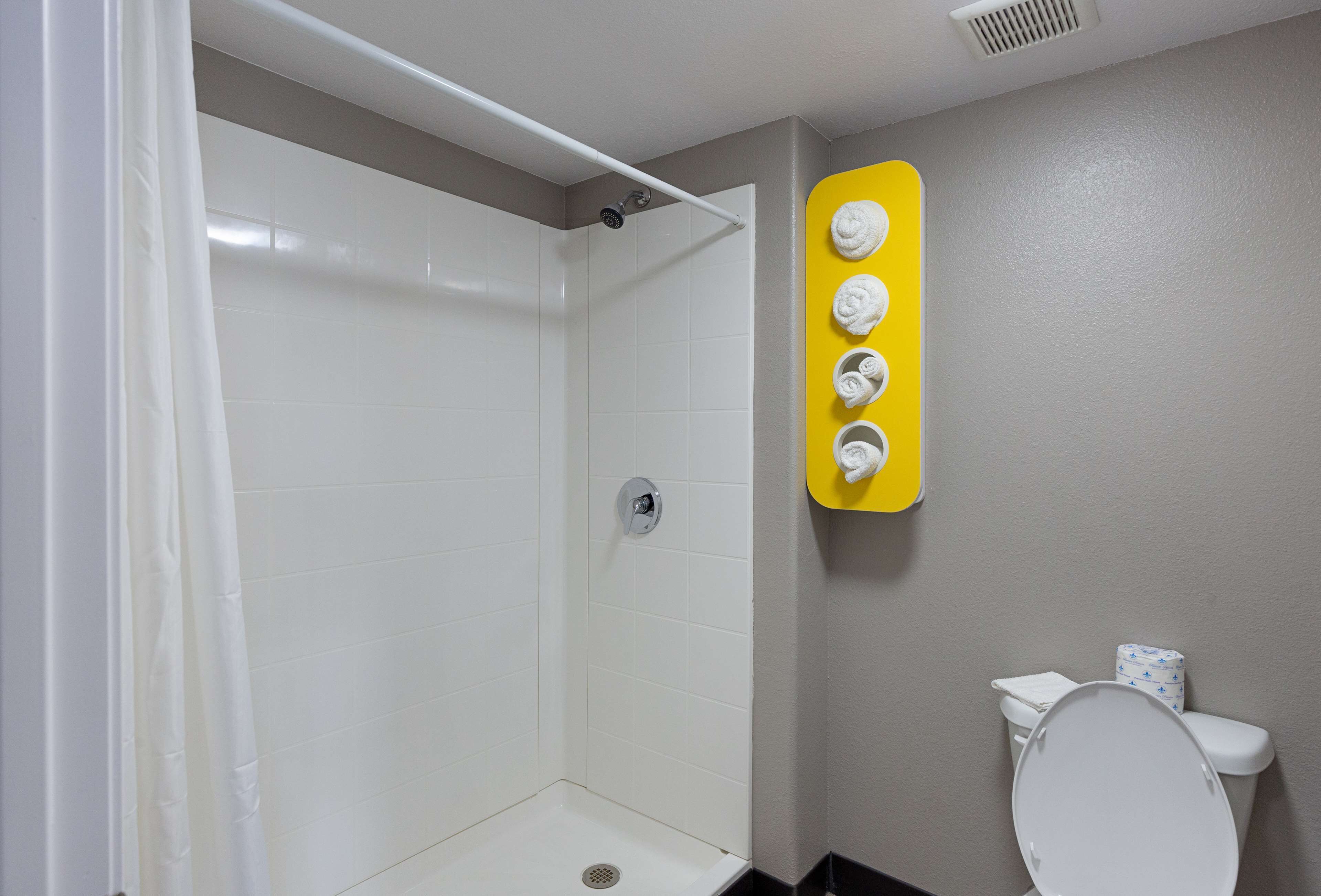 A bathroom with a shower, toilet, and a yellow towel rack.