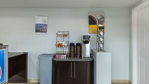 Un espace d’accueil comprenant une machine à café, une poubelle et un tableau d’affichage.
