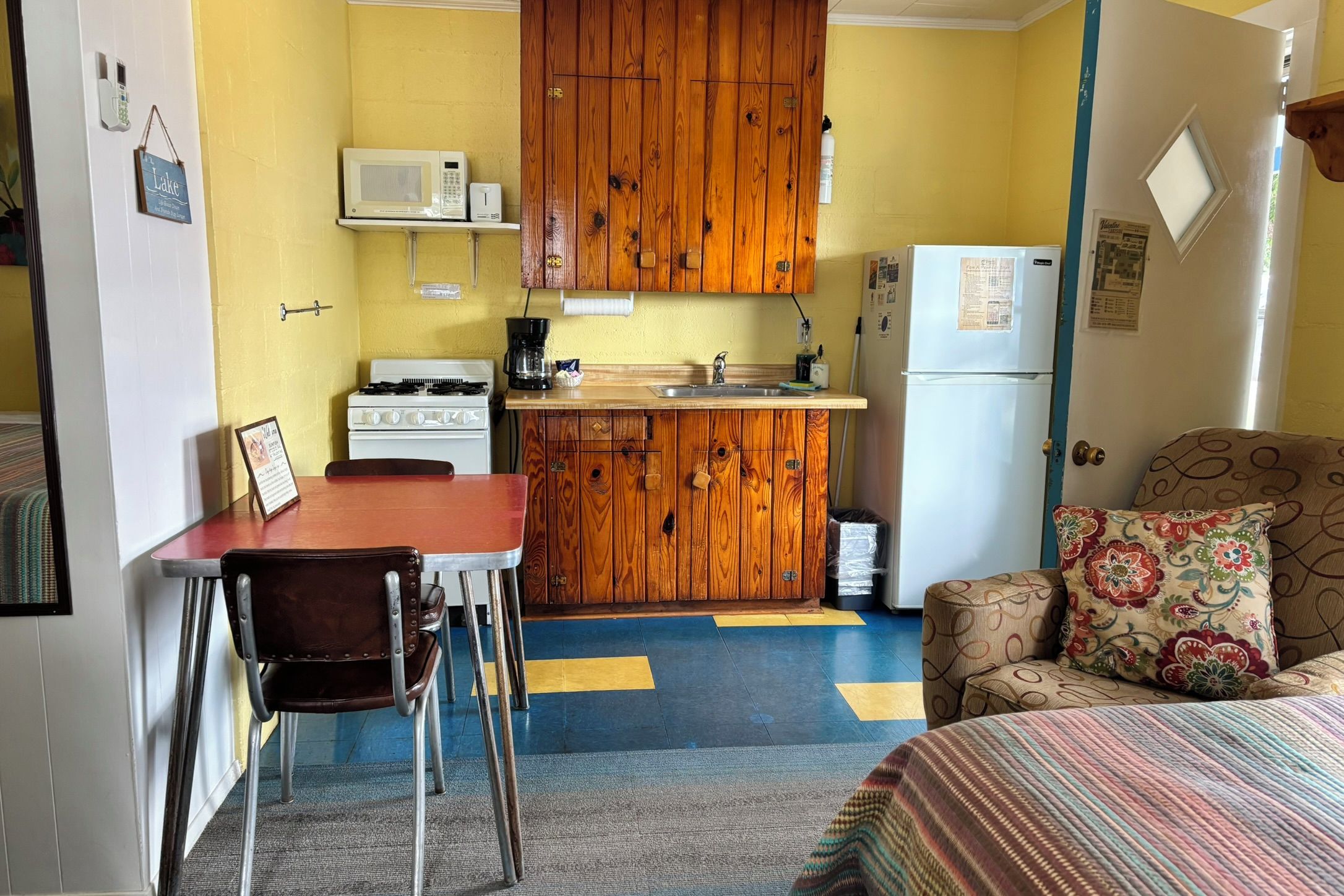 A compact kitchen with wooden cabinets, a stove, a microwave, and a refrigerator.
