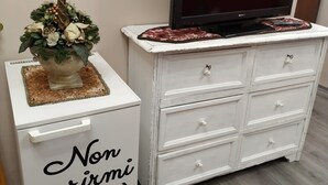 A white dresser with a flat-screen TV on top, drawers, and a decorative item with text on the front. - Casa Pif: quiet, pretty and welcoming (Frosinone)