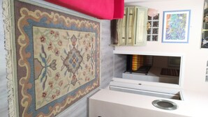 A room with a large patterned rug, a red chair, a white cabinet with glass doors, and a framed artwork on the wall. - Casa Pif: quiet, pretty and welcoming (Frosinone)