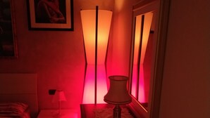 A dimly lit room with a bed, a nightstand, a lamp, and a framed picture on the wall. - Casa Pif: quiet, pretty and welcoming (Frosinone)