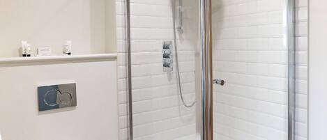 Un baño moderno con ducha acristalada, inodoro blanco y suelo de madera.
