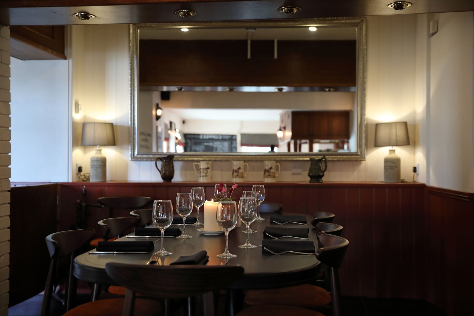 A dining area with a round table set for six, equipped with wine glasses and a candle.