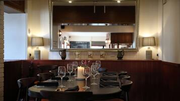 A dining area with a round table set for six, equipped with wine glasses and a candle.