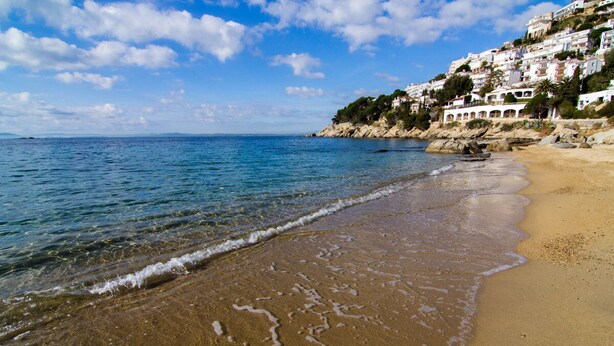 A beach with clear water, a sandy shore, and buildings on a hillside. - Agi Horitzo 11 Apartamento for rent in Roses Girona. (Roses)