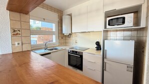 A kitchen with a wooden countertop, white cabinets, a built-in oven, a microwave, and a refrigerator. - Agi Horitzo 11 Apartamento for rent in Roses Girona. (Roses)