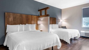 A hotel room with two beds, wooden headboards, a large window, and a wall-mounted air conditioner. - Extended Stay America Suites Colonial Heights Fort Lee (Colonial Heights)