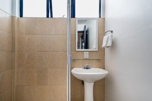 A bathroom with beige tiles, a white sink, a mirror, and a towel rack.