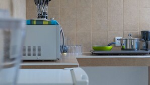Eine Küche mit Mikrowelle, Wasserkocher, einer grünen Schüssel und einem Topf auf der Arbeitsfläche.
