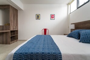 A bedroom with a bed, a red chair, a wooden wardrobe, and two framed pictures on the wall.