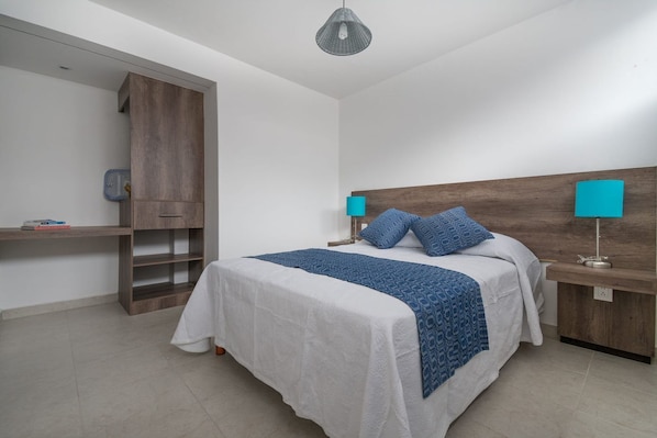 Ein Schlafzimmer mit einem Bett, Nachttischen, einem Kleiderschrank und einer Pendelleuchte.