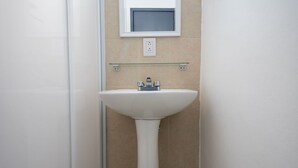 A bathroom with a pedestal sink, a mirror, and a glass shelf above the sink. - JUUB at THE SOUL OF OAXACA (Oaxaca)