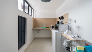 A compact kitchen with a sink, microwave, and a small refrigerator. There is a window providing natural light and a hanging light fixture. - JUUB at THE SOUL OF OAXACA (Oaxaca)
