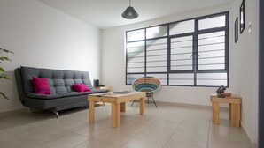 A modern living room with a grey sofa, a wooden coffee table, and a colorful chair. - JUUB at THE SOUL OF OAXACA (Oaxaca)