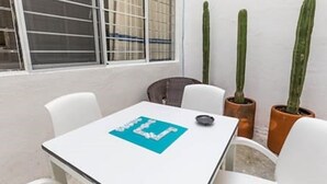 A small, white table with a blue placemat, two potted cacti, and a window with metal bars. - Oaxaca at your doorstep (Oaxaca)