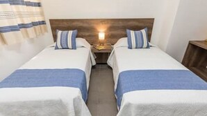 A hotel room with two single beds, each with a blue and white striped pillow and blanket. - Oaxaca at your doorstep (Oaxaca)