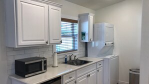 A kitchen with white cabinets, a microwave, a dishwasher, and a sink. - Cozy Private Casita (Tucson)