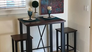 A small dining table with two stools, a decorative vase, and a wall art piece. - Cozy Private Casita (Tucson)