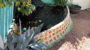 A small pond with decorative tiles, surrounded by plants and a blue wall. - Cozy Private Casita (Tucson)