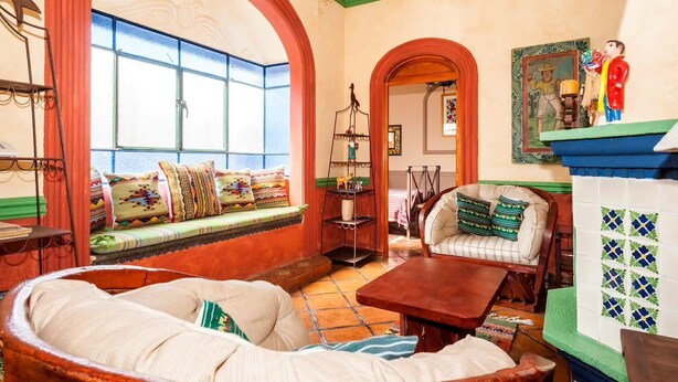 Uma sala de estar acolhedora com um espaço de estar circular, uma mesa de centro de madeira e um sofá com almofadas estampadas.
