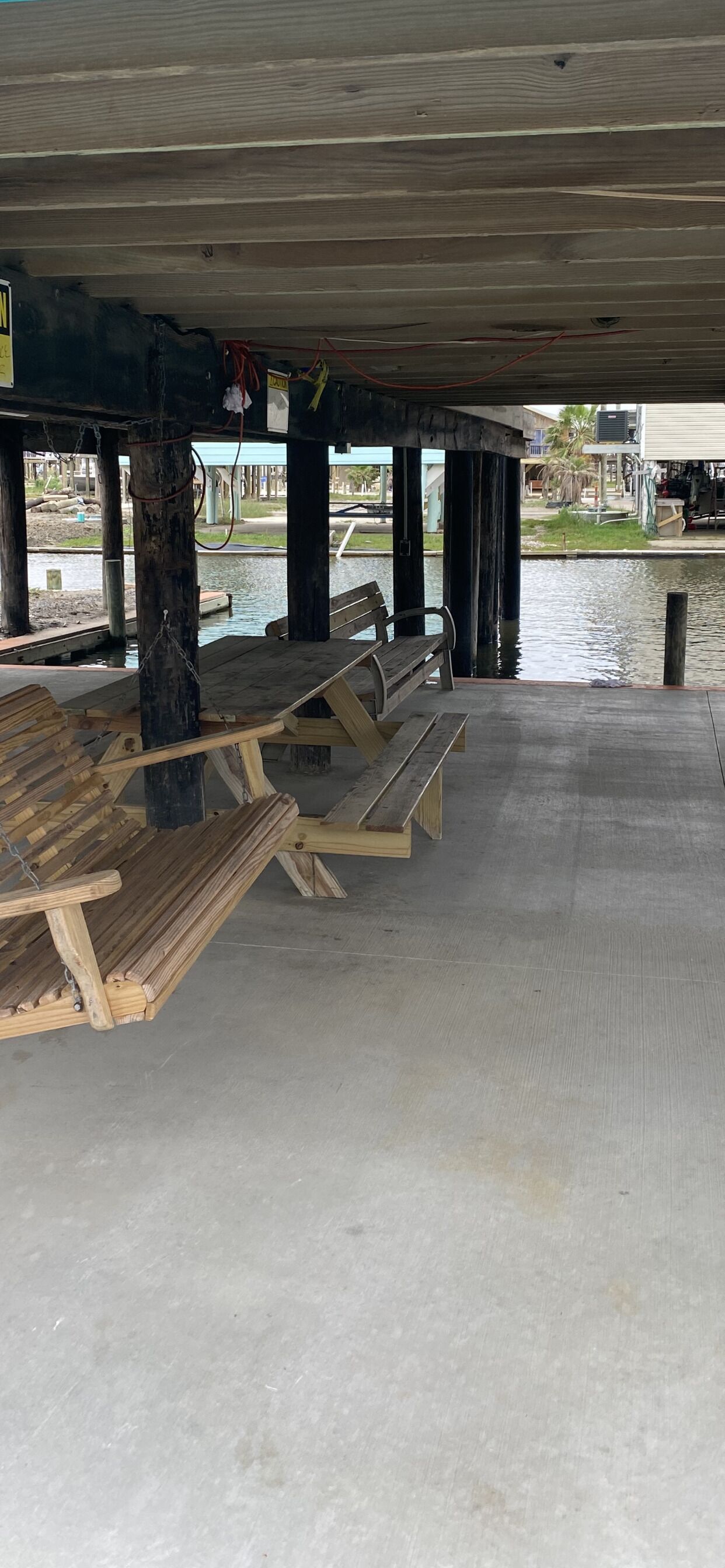 An empty outdoor seating area with wooden benches under a covered structure.