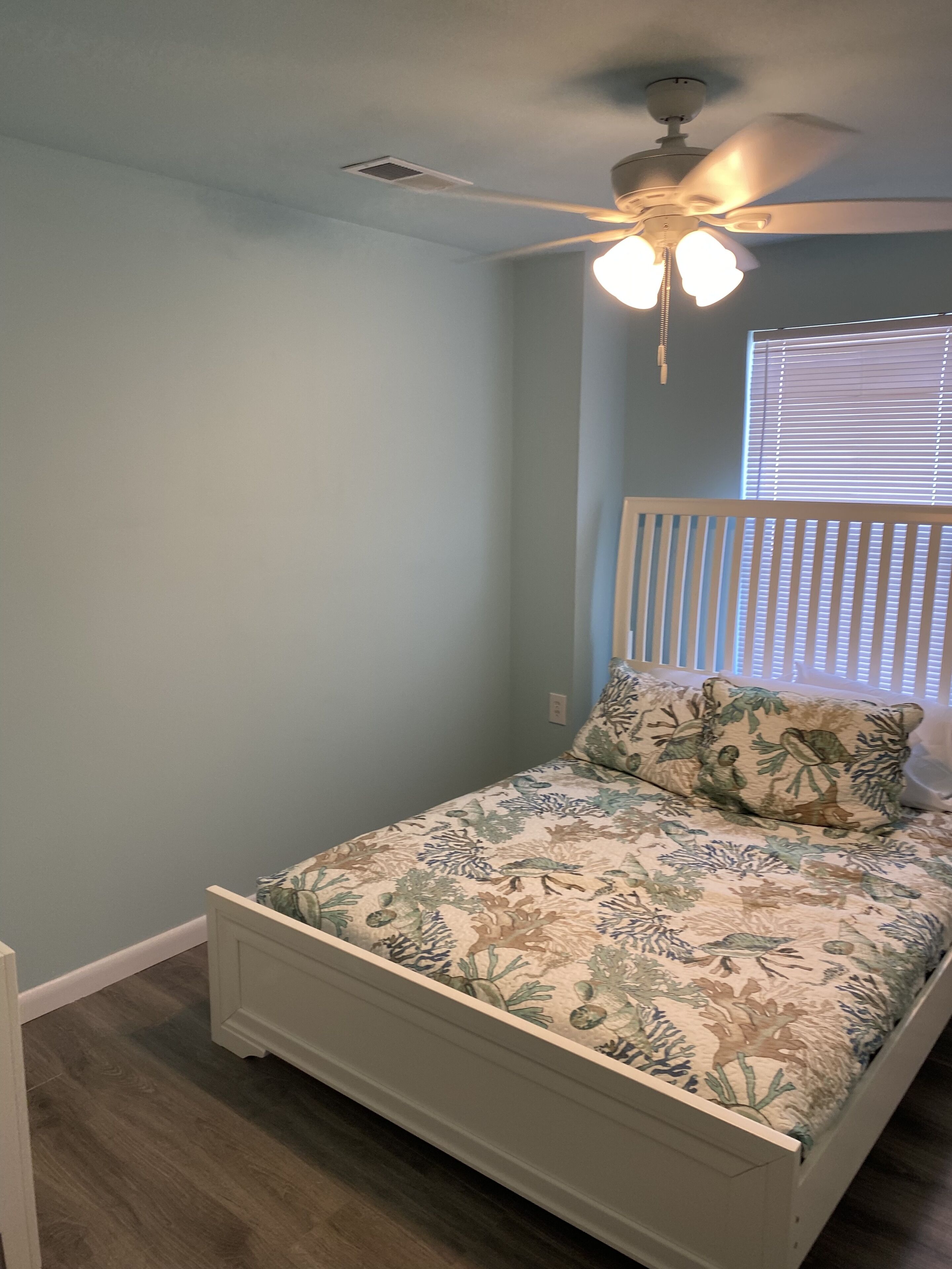 A bedroom with a bed, a ceiling fan, and a window with blinds.