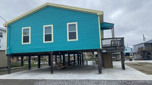 Une maison à deux étages, avec une façade bleue et une véranda.