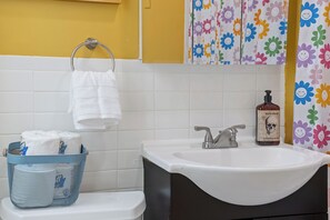 Bathroom features a white sink, toilet paper basket, and a towel hanging from a metal ring.