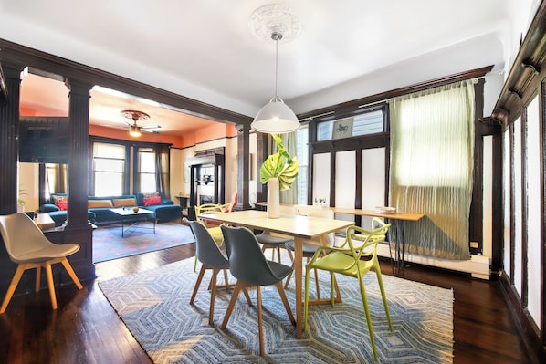 A dining area with a table, chairs, and a hanging light fixture.