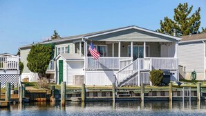 A waterfront house with a porch, a flag, and a dock.