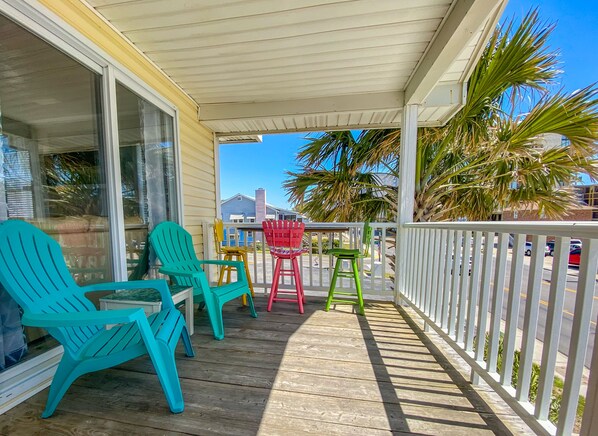 A wooden deck with colorful Adirondack chairs, a small table, and a railing. - BeachHouse, Walk to Beach, Family-Friendly, Mins. to Attractions Golf Waterparks (North Myrtle Beach)
