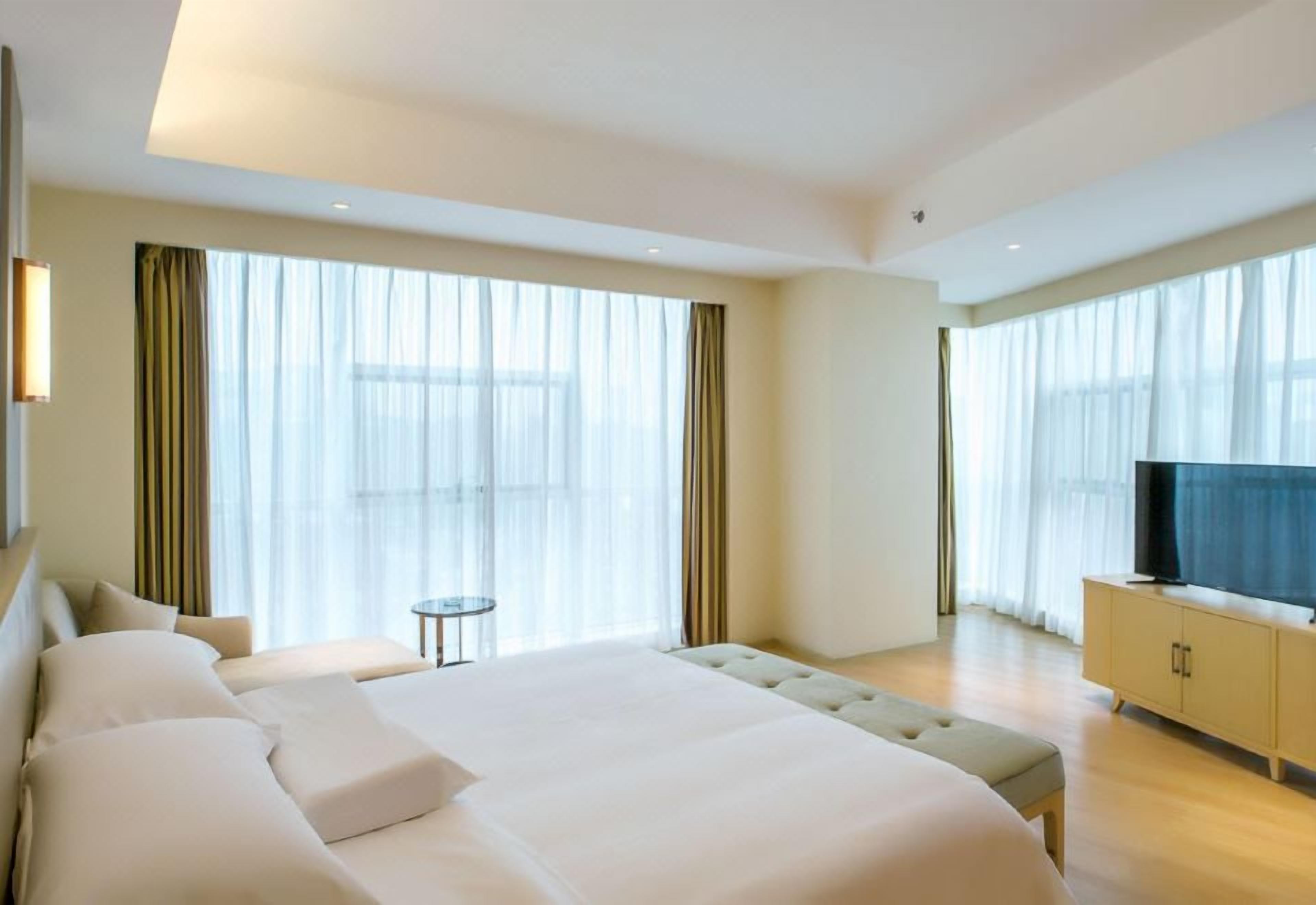 A modern hotel room with a large bed, a television, and a small table.
