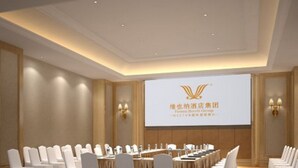 Sala de conferência com uma mesa comprida, cadeiras brancas e uma tela de projeção exibindo informações do grupo hoteleiro.